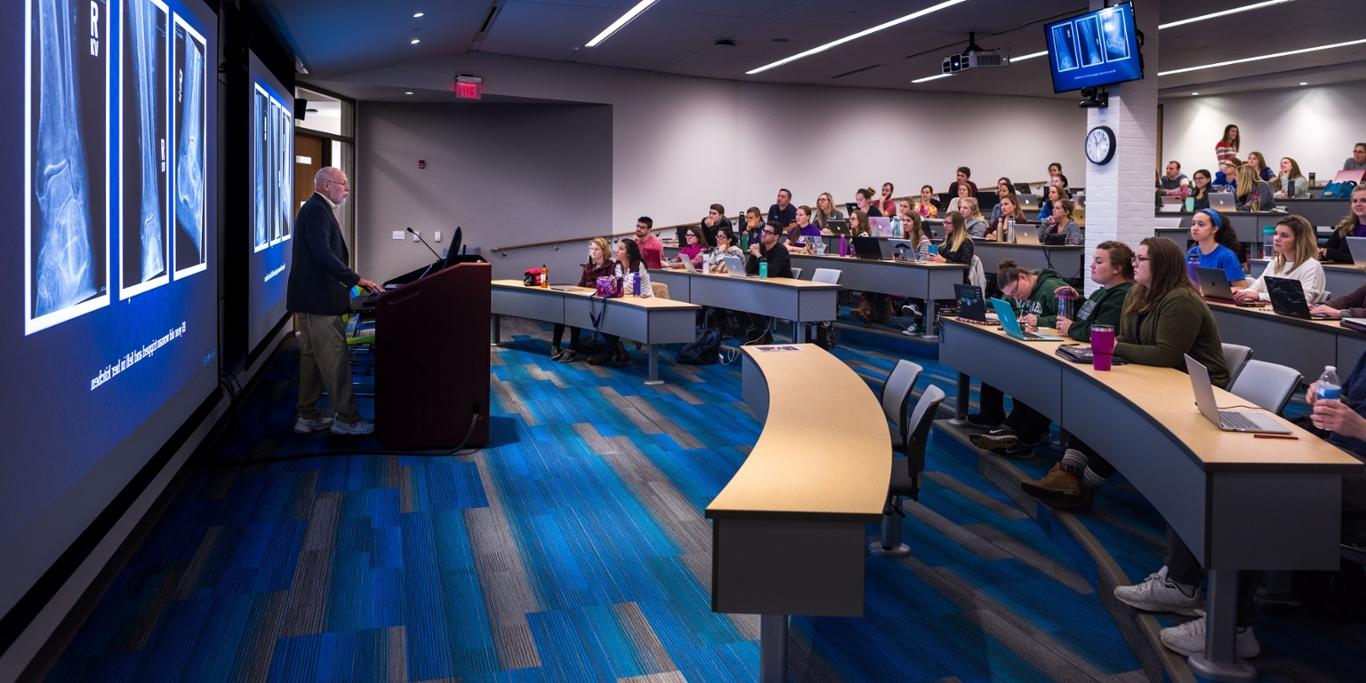 Photo of a professor teaching a classroom of Chatham University students in an auditorium at the Eastside campus. 